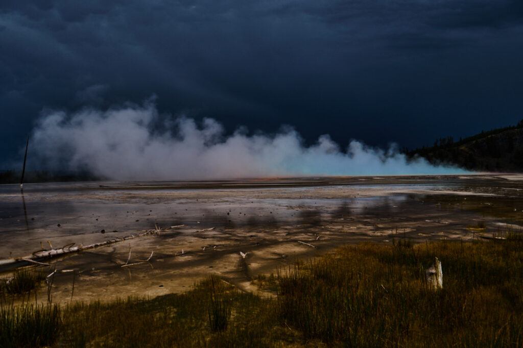 Grand Prismatic Spring in Yellowstone National Park viewed from the side after a passing storm, its famous colors visible in the steam